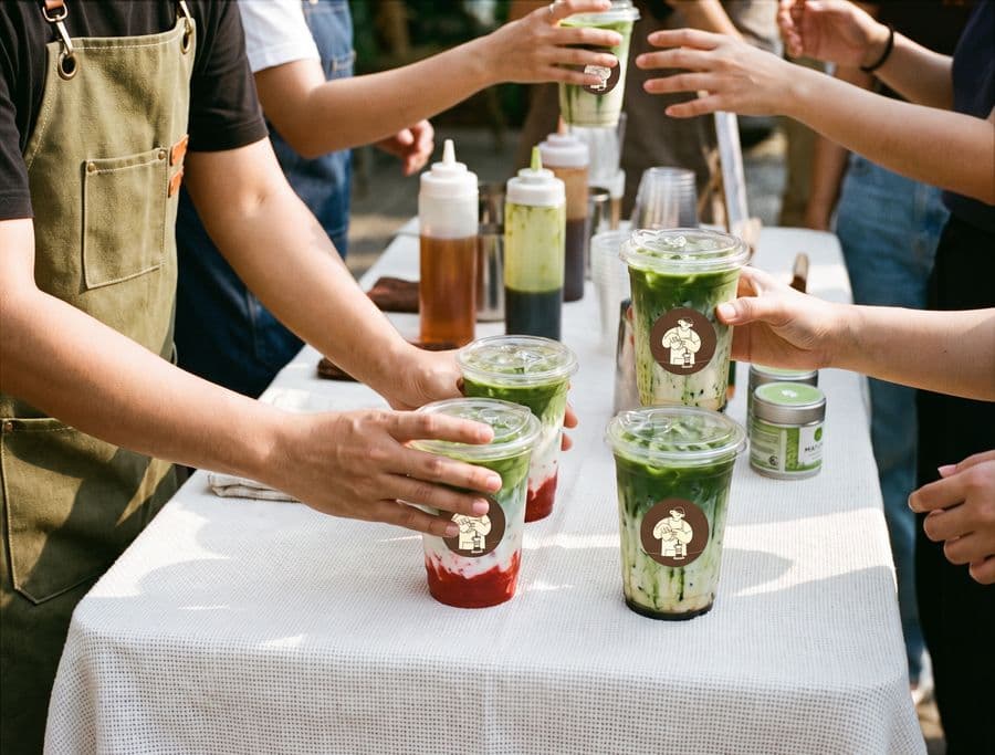 Iced matcha drinks handed across the pop-up table